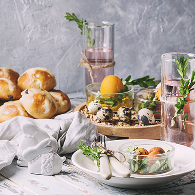 Cocktails garnished with rosemary with hot cross buns and easter eggs