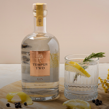 Bottle and glass of Tempus Two Prosecco Gin with lemon and rosemary
