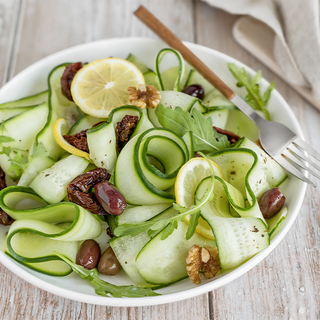 Zucchini salad with olives and nut and a fork in a bowl