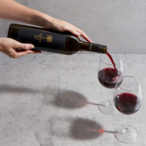 Tempus Two red wine being poured into two glasses with a grey background